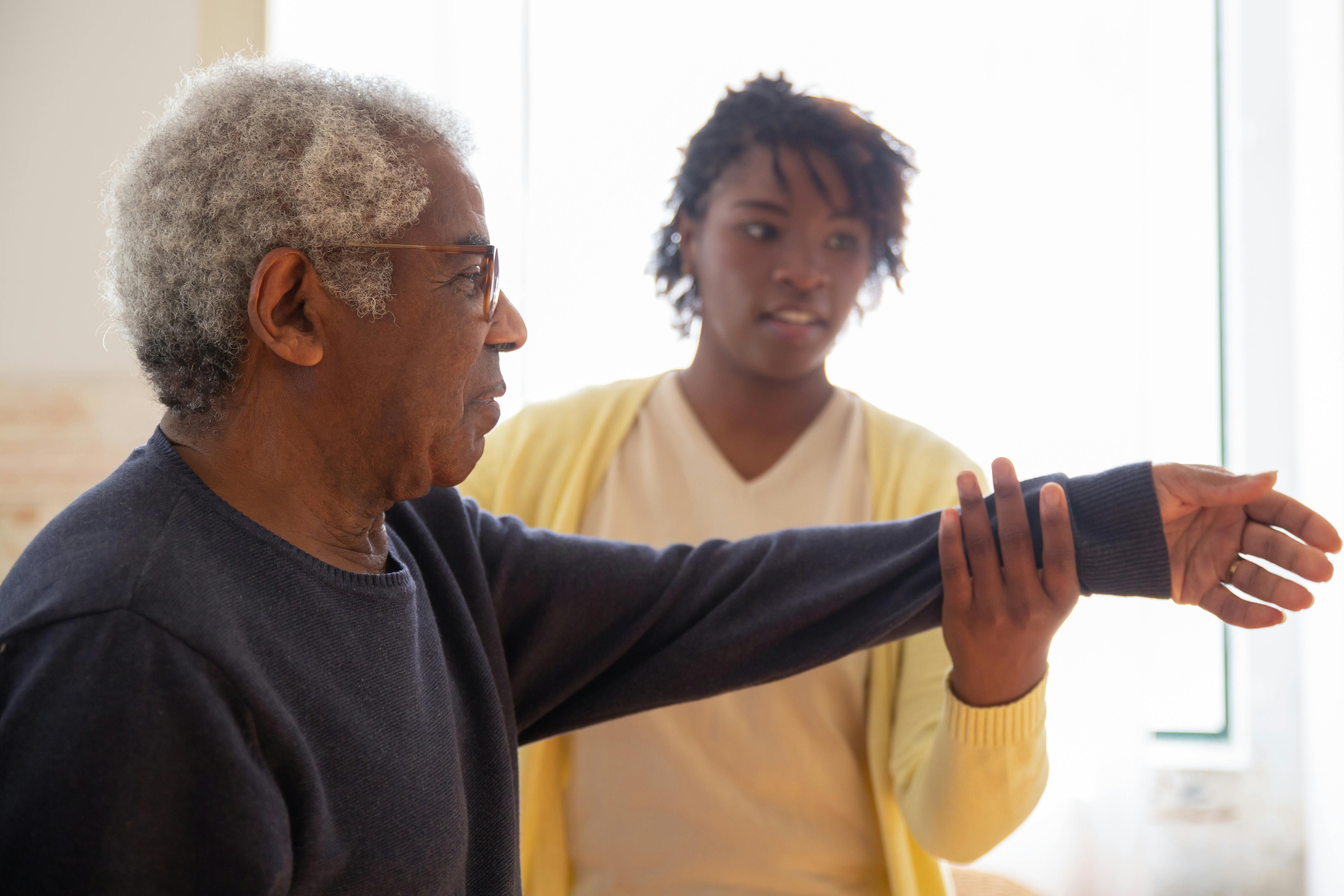 Home health caregiver assisting an elderly man with physical therapy exercises in Philadelphia
